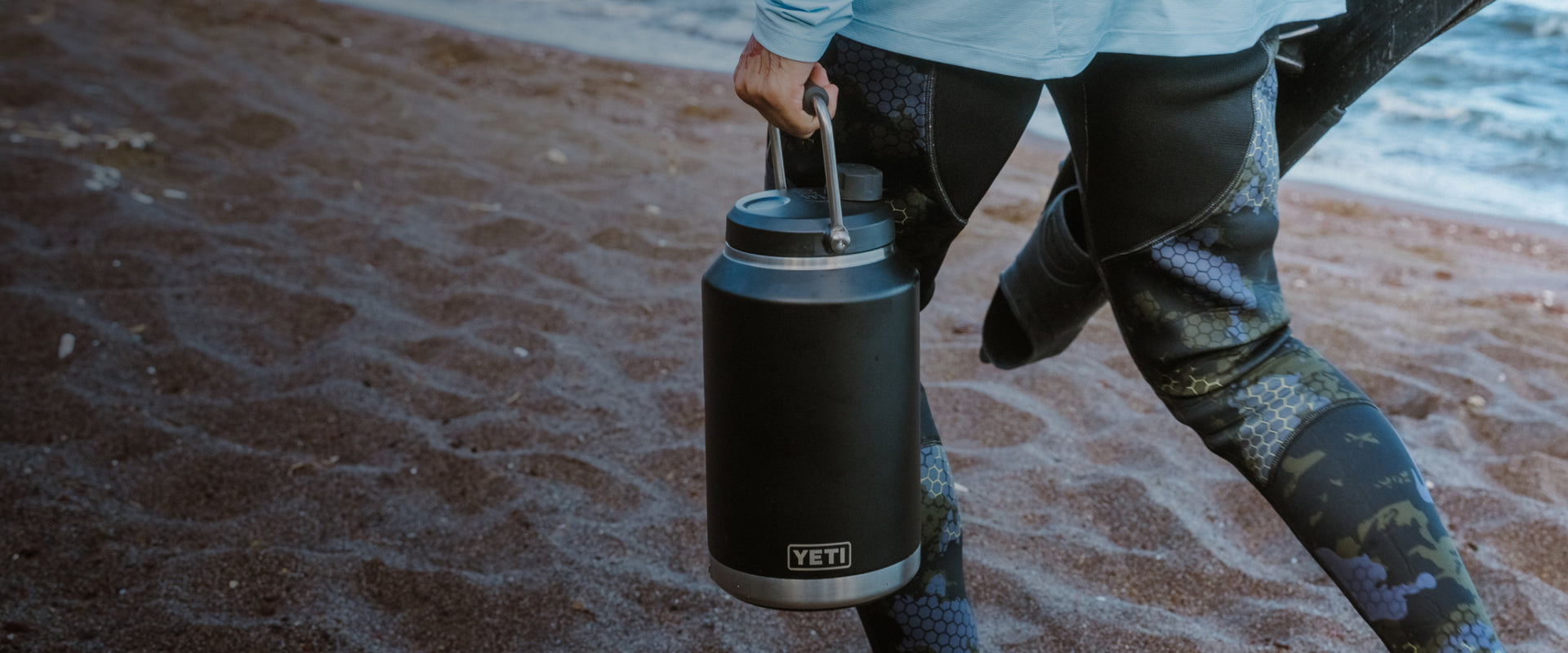 Person holding a YETI jug on a beach