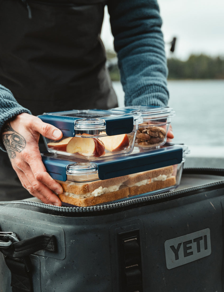 Person holding a set of food containers with a YETI cooler in the background