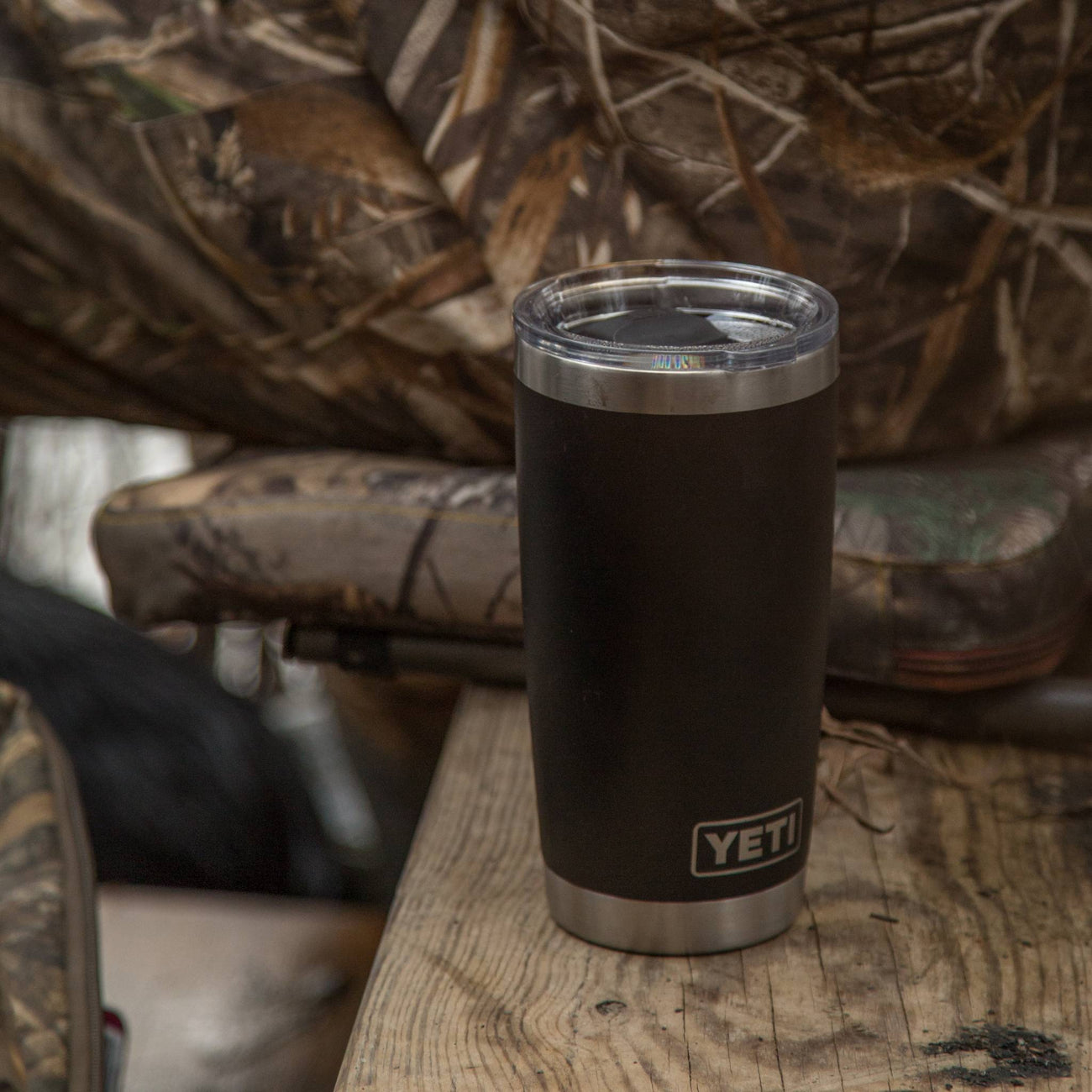 yeti tumbler on a wooden surface with camouflage in the background