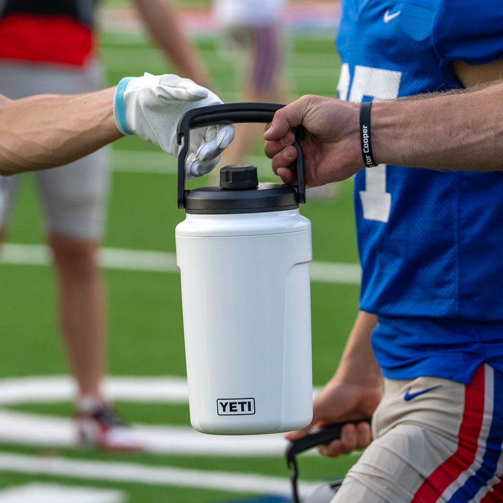 Football players passing a Yeti Silo Jug in white.