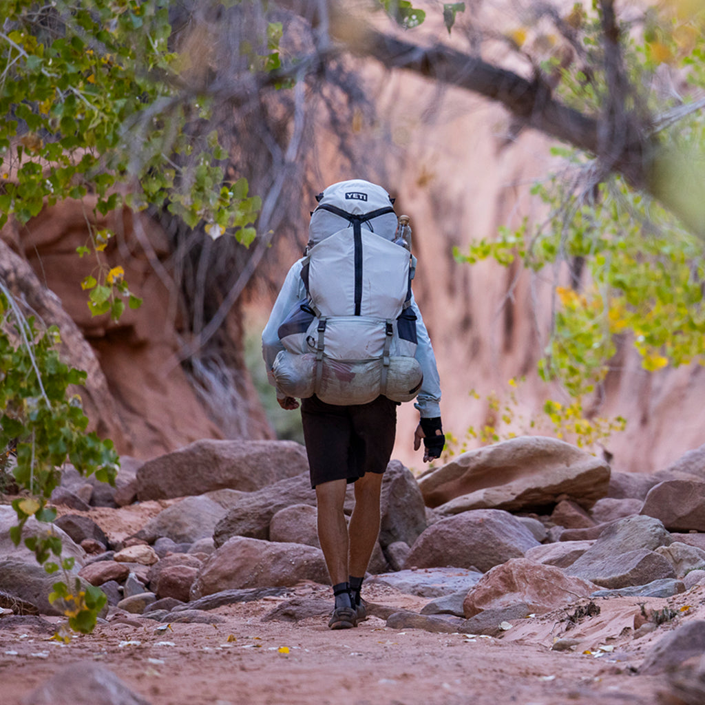 Person hiking through a rocky landscape with a large backpack