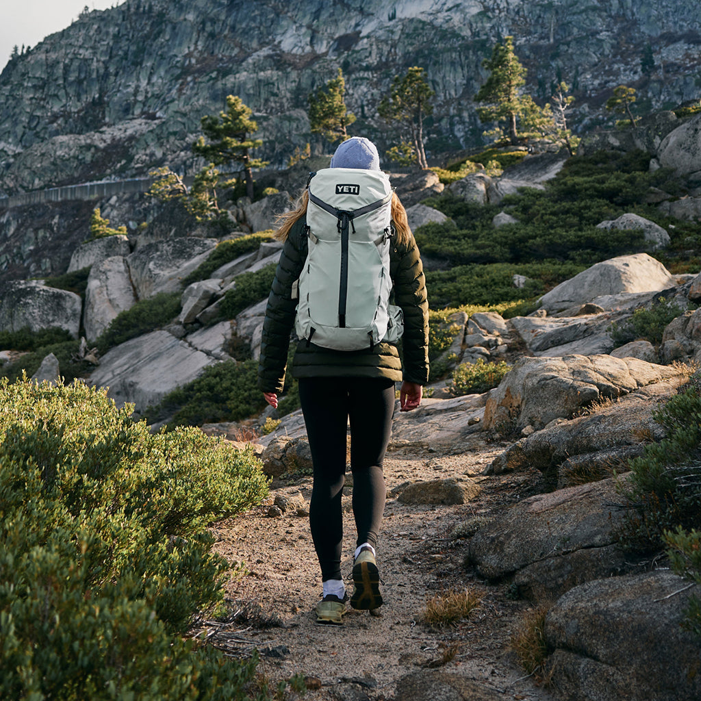 Person hiking on a mountain trail with a YETI backpack