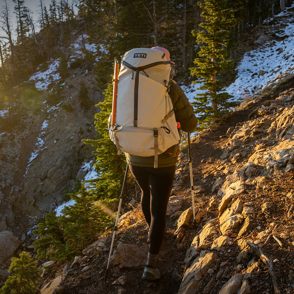 Person hiking on a mountain trail with a large backpack