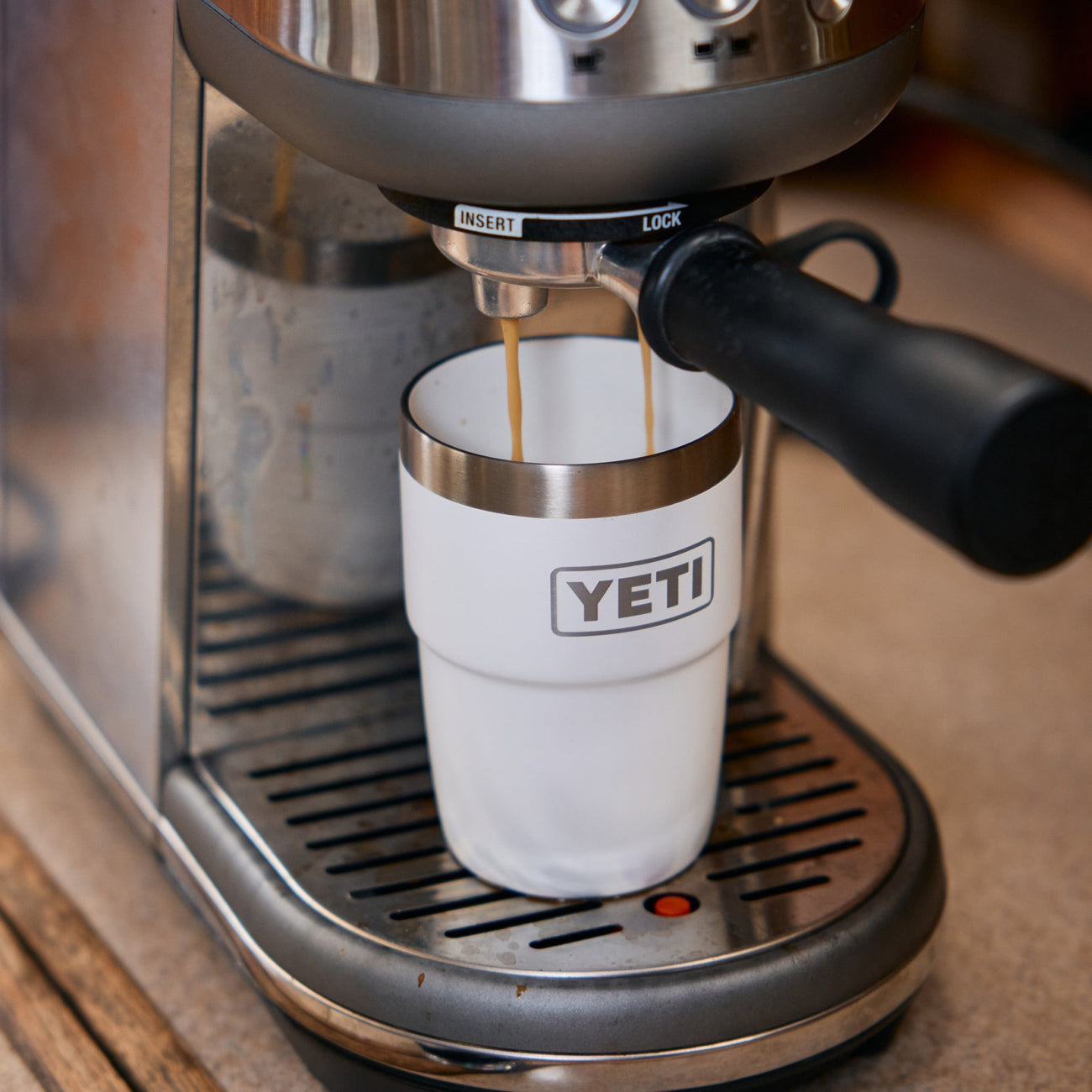 Espresso machine pouring coffee into a YETI-branded tumbler.