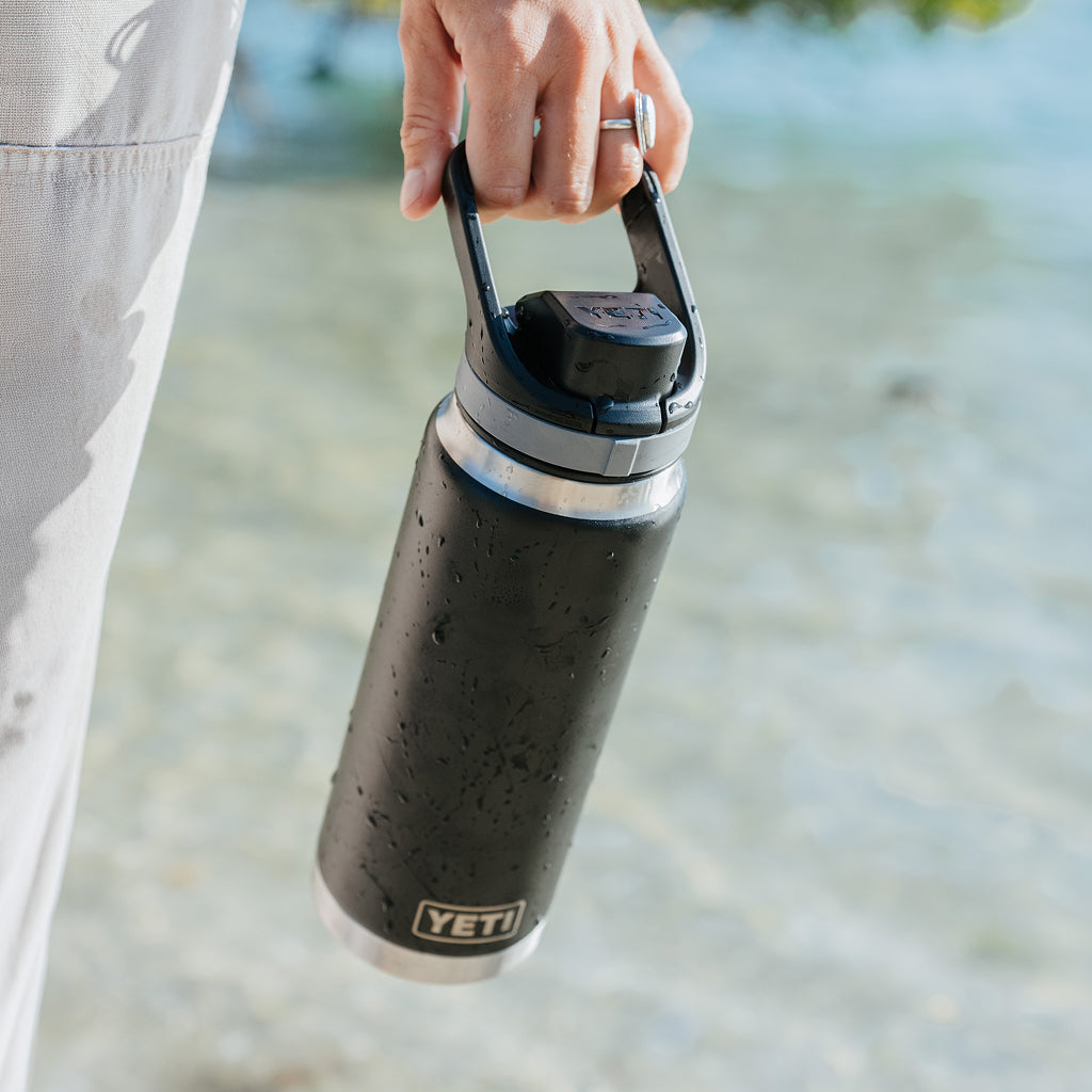 Person holding a black YETI water bottle outdoors
