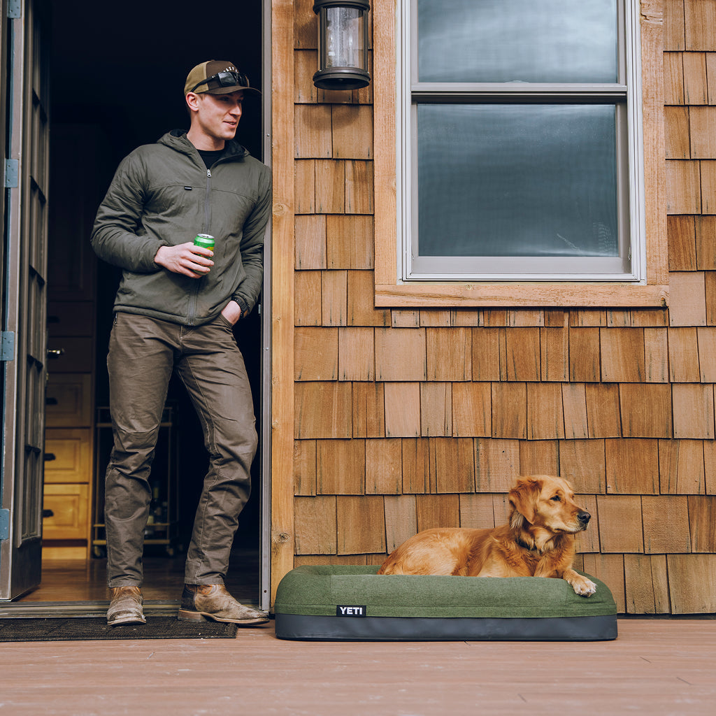 Man with a  dog on a YETI Boomer Dog Bed