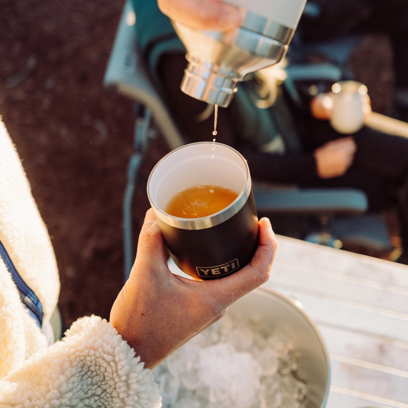Person pouring a cocktail into a YETI insulated lowball outdoors.