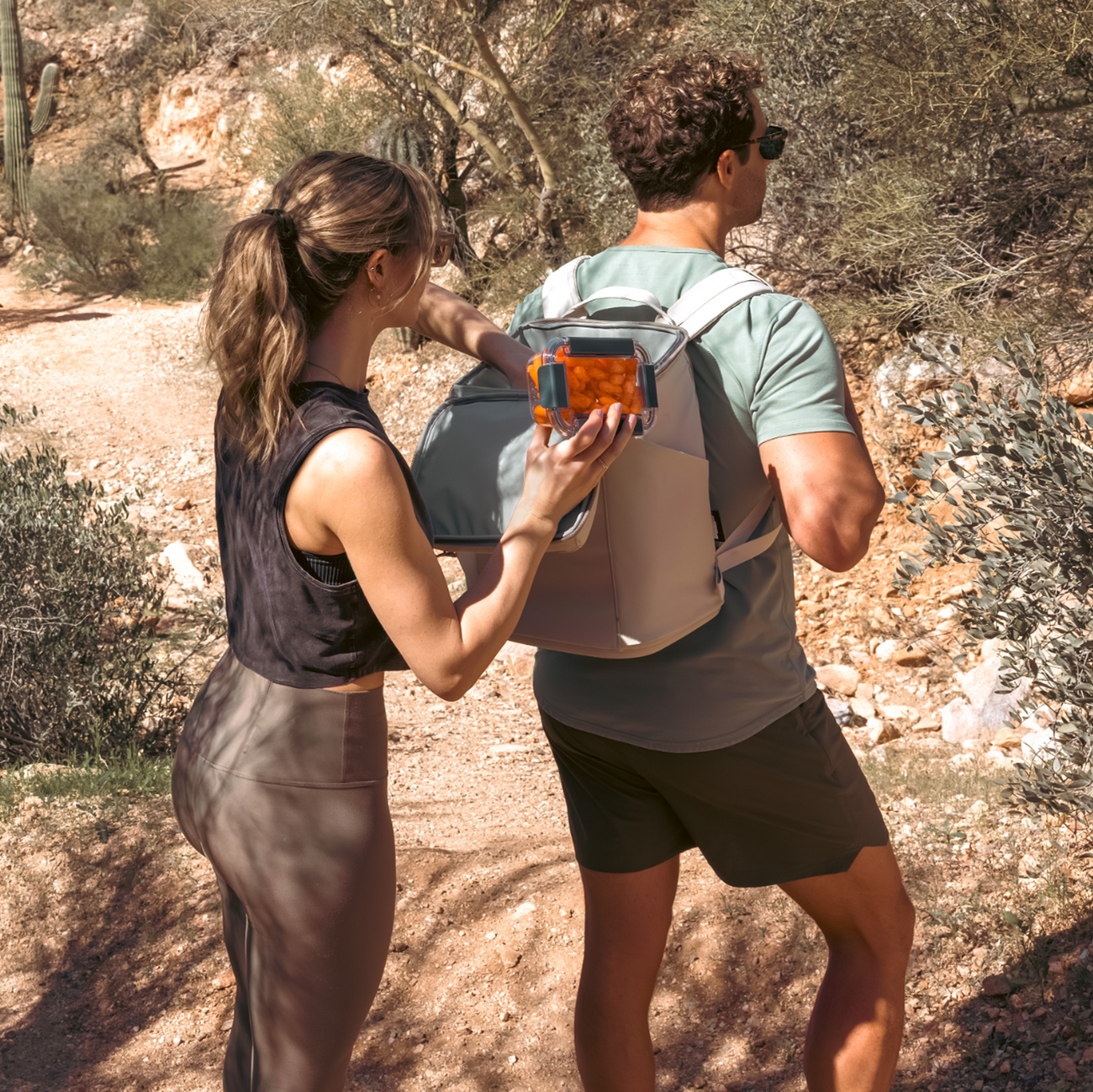 Two people hiking and using a YETI backpack cooler