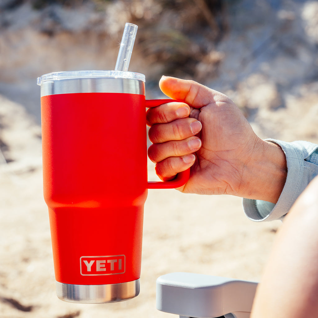 Hand holding a red YETI straw mug outdoors