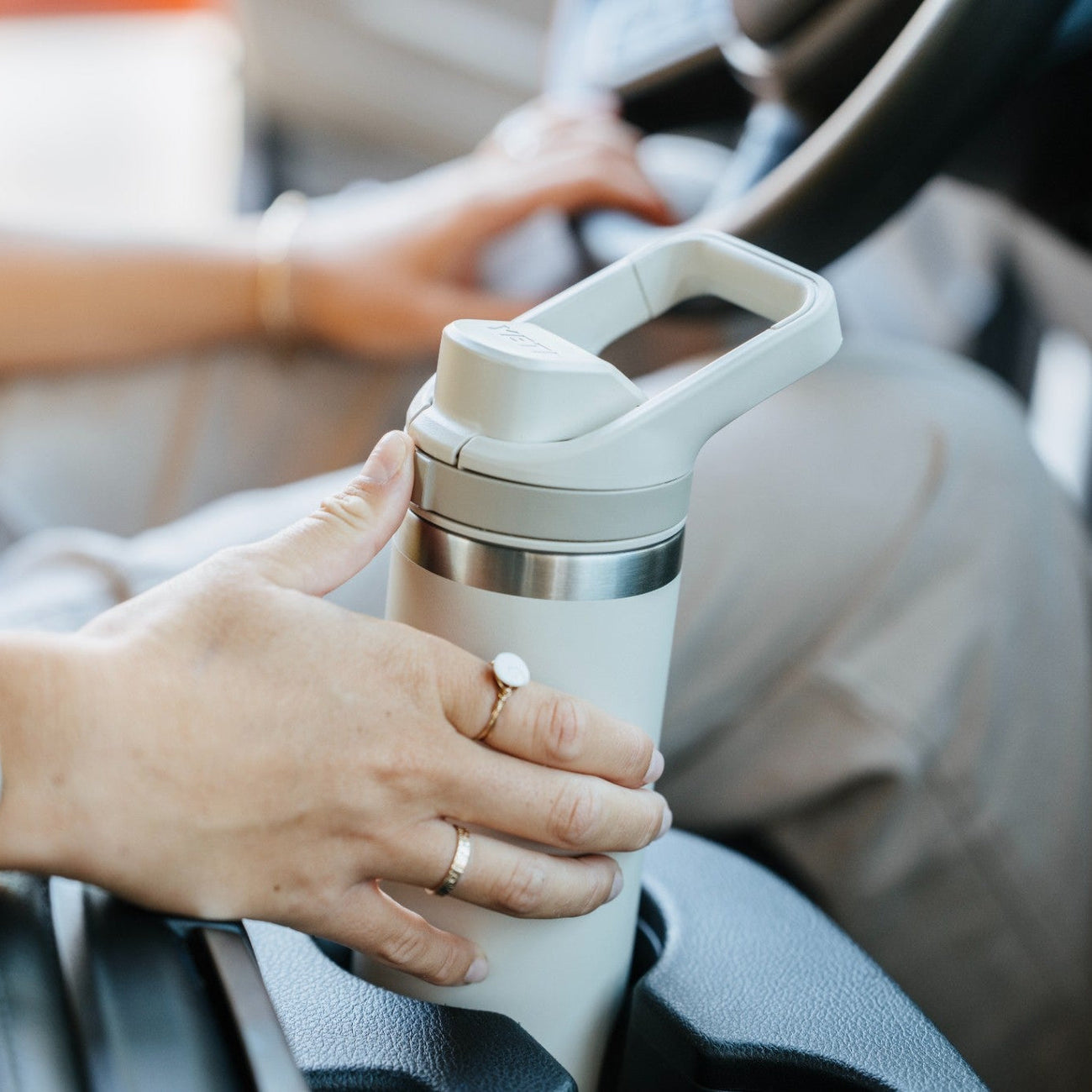 Person holding a white water bottle in a car