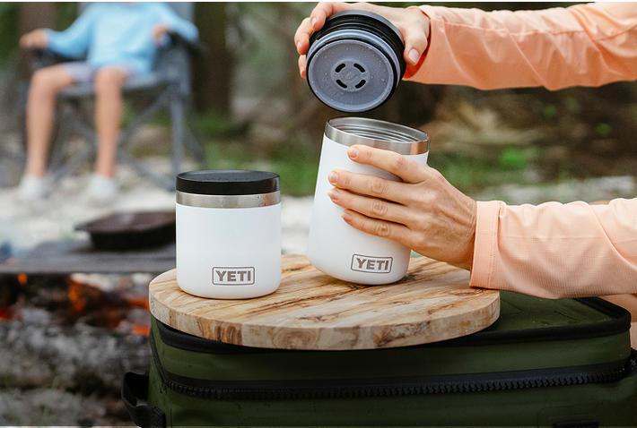 Person using a YETI brand insulated mug outdoors, likely camping.