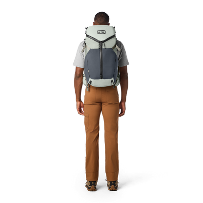 Person wearing a YETI backpack on a white background