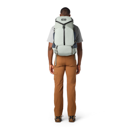 Person wearing a YETI backpack on a white background