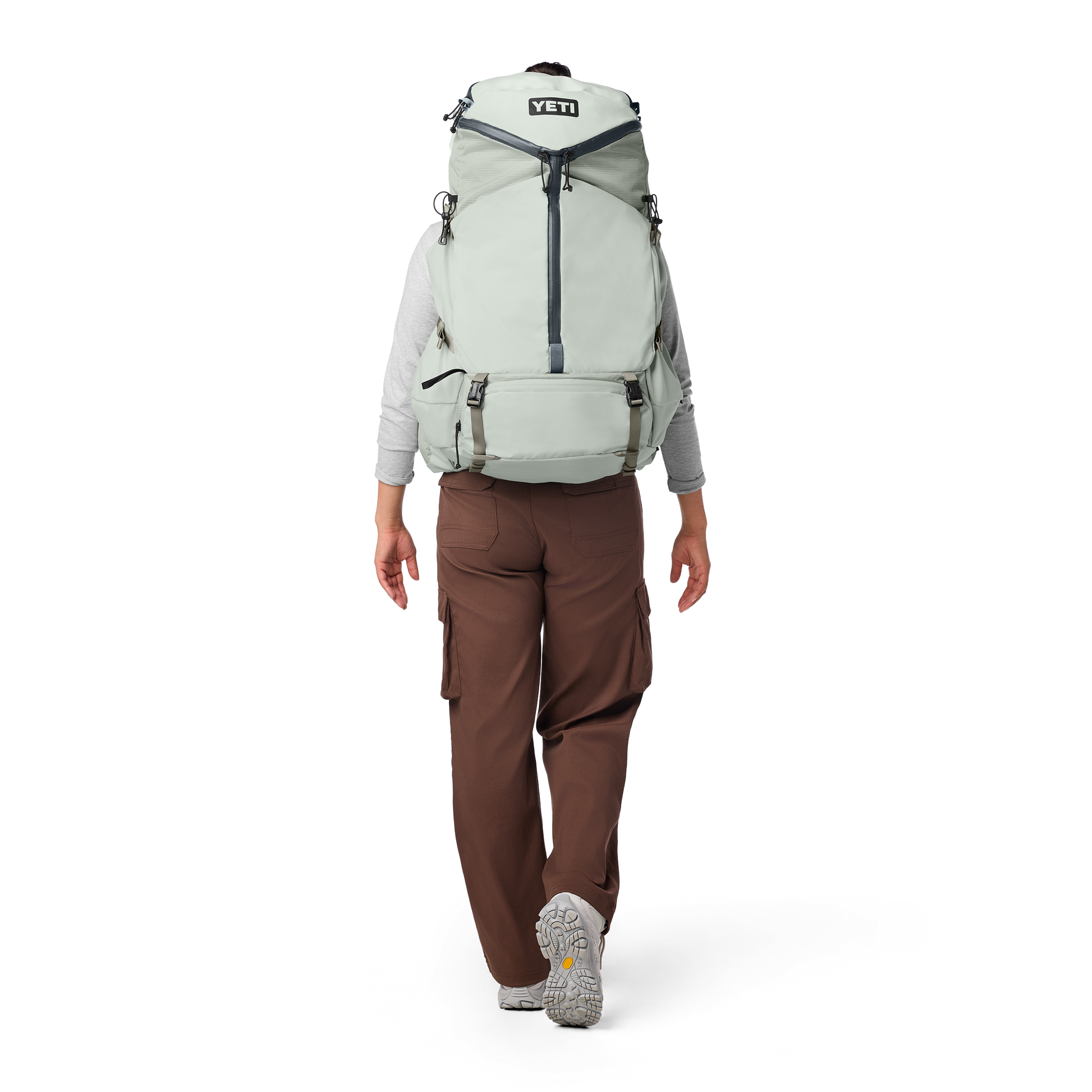 Person wearing a large green backpack with YETI logo on a white background