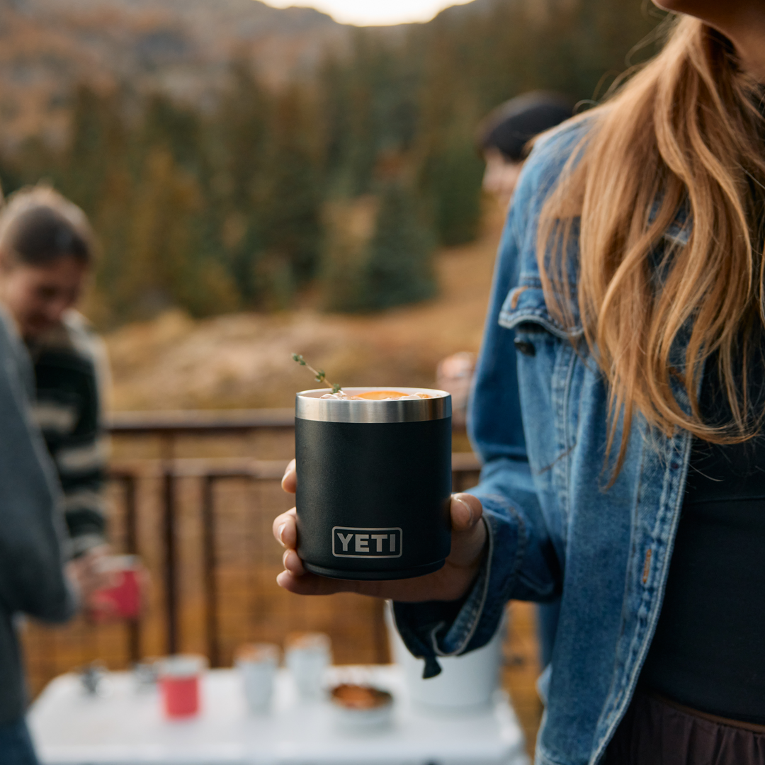 Person holding a YETI mug outdoors with blurred background