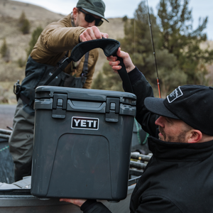 Two men with a YETI cooler outdoors, likely in a hunting or camping setting.